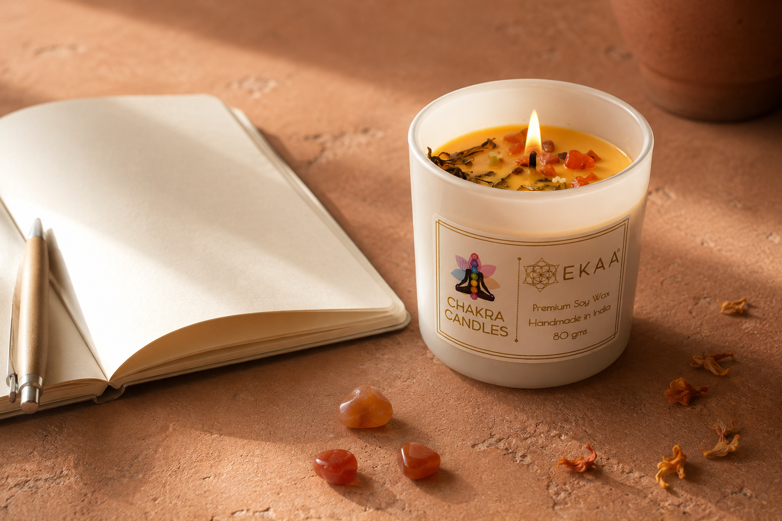 Sacral chakra candles India by EKAA, an orange soy candle with carnelian and a journal in warm light